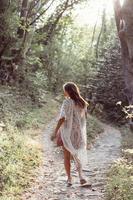 Beautiful, young girl walks at the foot of the mountain along photo