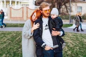 feliz mamá papá e hijo abrazándose en el parque foto