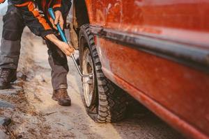 Man unscrews the bolts on the wheel photo