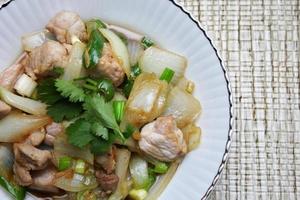 Stir-fried pork with chilli with onions and spring onions served in a white plate, Stir-fried pork with chilli is a popular Thai dish that Thai people eat. photo