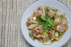 Stir-fried pork with chilli with onions and spring onions served in a white plate, Stir-fried pork with chilli is a popular Thai dish that Thai people eat. photo