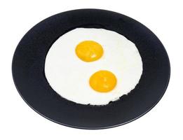 two fried eggs on black plate isolated on white photo