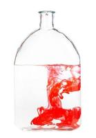 red watercolour dissolves in water in glass flask photo