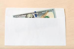 one hundred-dollar bill in open envelope on table photo