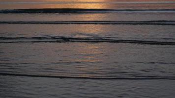 schöne Aussicht auf den Sonnenuntergang am Strand. Farbiger Strandsonnenuntergang mit goldenem Licht, das sich auf der Wasseroberfläche und sanften Wellen widerspiegelt. sommerferien und reisekonzept.