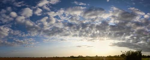 Panorama of stunning clouds in the sky above an agricultural field. photo