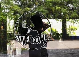 Black sticker welcome with message Welocme on glass door at coffee shop photo
