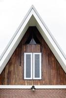 White window with wooden wall on triangular end of roof photo