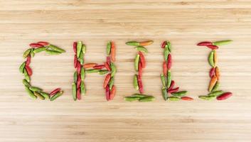 Top view colorful bird chilli with message CHILI on wooden background photo
