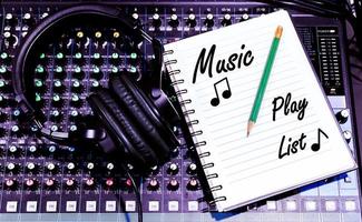 Top view black headphone and notebook with Music Play List message on console sound board mixer photo