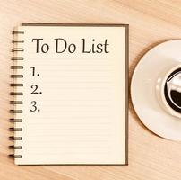 cuaderno de vista superior escribir mensaje para hacer lista y lista de números con taza de café en la mesa foto