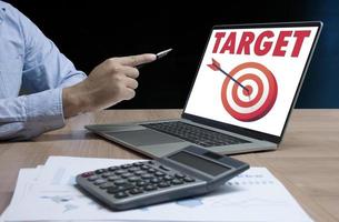 Businessman hand holding pen to display laptop with message Target and red dart arrow hitting on dartboard icon photo