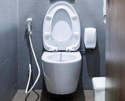 Ceramic white toilet bowl with grey wall in bathroom. photo