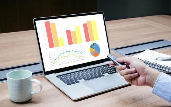 Businessman hand hold remote control slide with mock up chart slide show presentation on display laptop on table photo