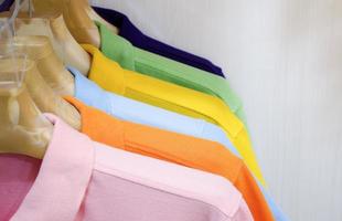 Many colorful shirts hanging on a rack photo