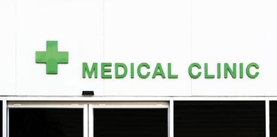 clínica médica de texto verde con icono de cruz verde en el edificio