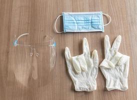 Top view rubber gloves showing gesturing victory and love symbol with face shield face mask on table photo