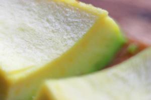 Slices of avocado on wooden background close up picture. Bad cholesterol prevention food photo