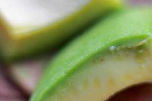 Slices of avocado on wooden background close up picture. Bad cholesterol prevention food photo