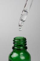 falling drop from a pipette into a green jar. natural and beauty skin care photo