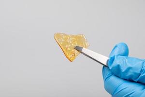 yellow piece of medical cannabis wax with a high content of THC in hand on gray background photo