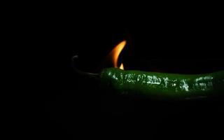 flaming green chili pepper close up on dark background photo