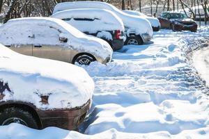 snow-covered cars on car parking in winter photo