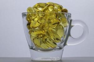 aceite de pescado omega 3 la cápsula está en un vaso transparente. Aislado en un fondo blanco. foto