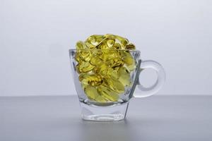 aceite de pescado omega 3 la cápsula está en un vaso transparente. Aislado en un fondo blanco. foto