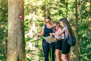 Group of hikers looks at a map beside a tree with a hiking trail sign photo