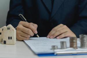 Sign the house approval document. Real estate appraisal, buy and sell houses, business concept finance.businessman holding pen and signing documents at desk photo