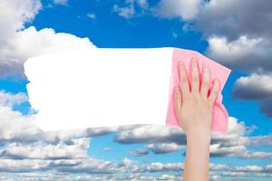 la mano elimina las nubes blancas en el cielo azul con un trapo rosa foto