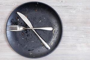 crossed knife and fork on plate on gray table photo