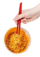 hand keeps red chopsticks with instant noodles photo