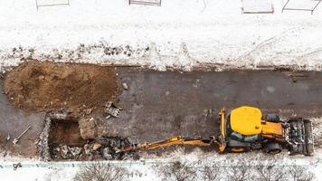 tractor digging road to change sewer pipes photo