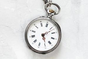 old pocket watch on light gray plaster surface photo