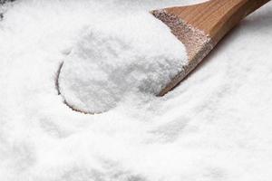 wooden spoon with dextrose sugar close up on pile photo