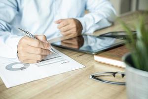 business documents on office table with digital tablet and graph business with social network diagram and man working in the office photo