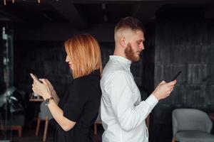 Young people stand with their backs to each other with a smartphones in hands. photo