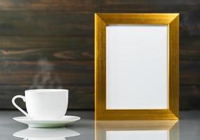 maqueta de imagen con marco dorado y taza de café foto