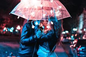 Guy and girl kissing under an umbrella photo