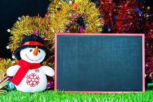 Snow man on green grass with chalkboard photo