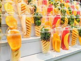 Mix fruits in a plastic glass on wooden shelves photo