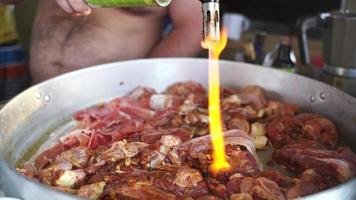 A man with a torch burns the surface of the meat photo