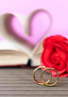 anillo de bodas con páginas de libro en forma de corazón curvo con rosa roja foto