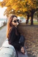 mujer atractiva que usa un teléfono inteligente al aire libre en el parque foto