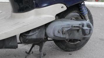 roda traseira com apoio para os pés em uma scooter velha estacionada. close-up de pneus de uma scooter. suspensão traseira da scooter. close-up da roda traseira de uma mini motocicleta. video