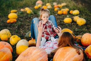 mother and daughter lie between pumpkins photo