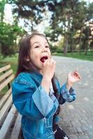 niña sentada en un banco con dulces foto