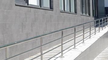 A ramp with stainless steel handrails for wheelchairs, bicycles and strollers with children in front of the building. Handrail for lifting a wheelchair. Shiny stainless steel handrail. video